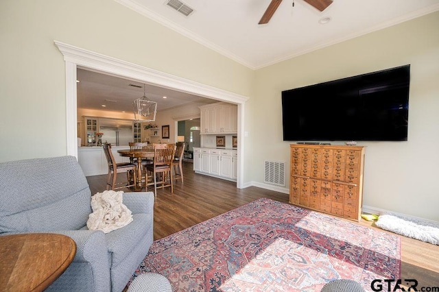 living room featuring dark wood finished floors, ornamental molding, visible vents, and ceiling fan