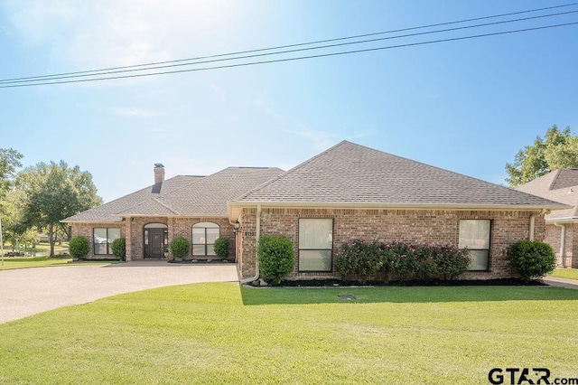 view of front facade featuring a front yard, brick siding, roof with shingles, and curved driveway