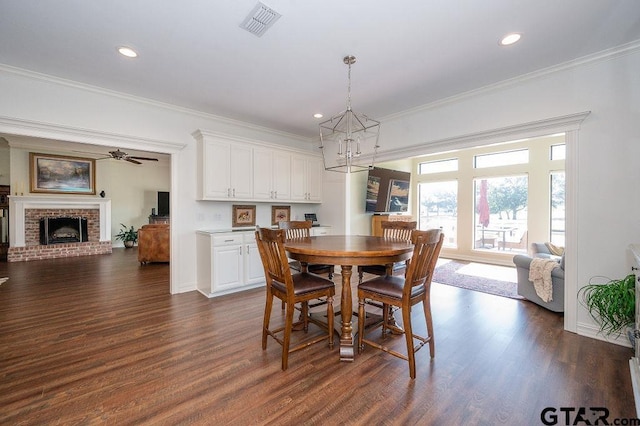 dining area featuring visible vents, dark wood-type flooring, ornamental molding, recessed lighting, and a fireplace