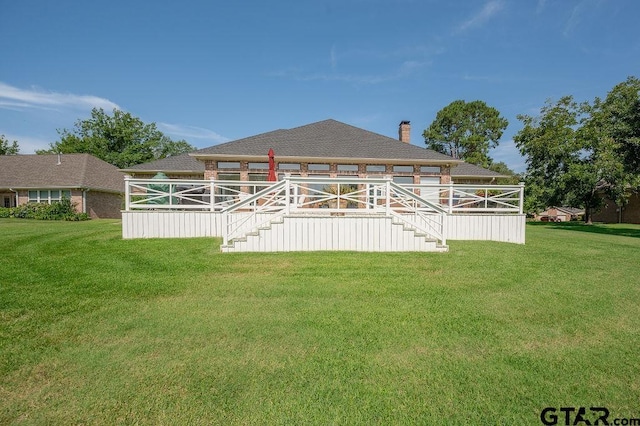 back of house featuring stairway, a lawn, a chimney, and a shingled roof