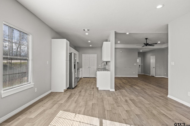 kitchen featuring ceiling fan, sink, light hardwood / wood-style flooring, white cabinetry, and stainless steel refrigerator