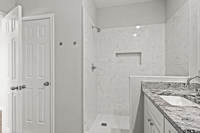 bathroom with a tile shower and vanity