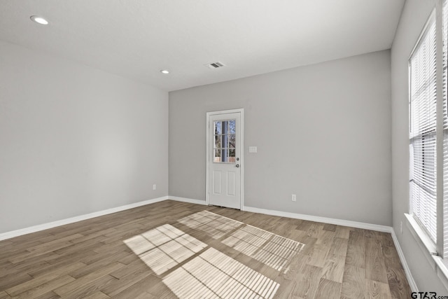 spare room featuring a wealth of natural light and light hardwood / wood-style floors