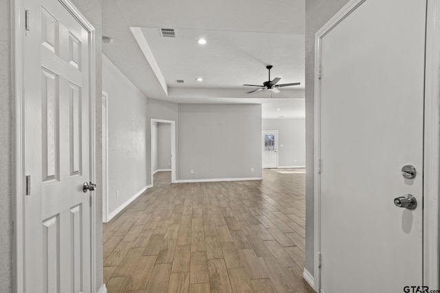 hall featuring light hardwood / wood-style floors and a raised ceiling