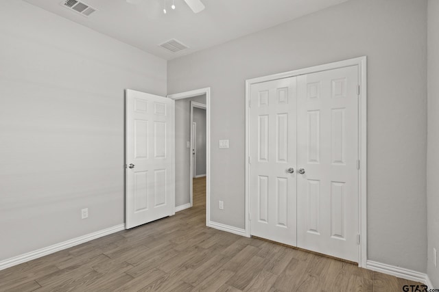 unfurnished bedroom with ceiling fan, a closet, and light wood-type flooring