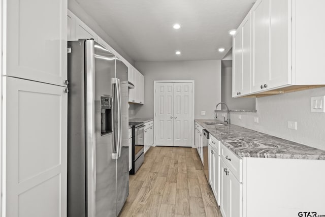 kitchen with light stone counters, sink, white cabinets, and stainless steel appliances