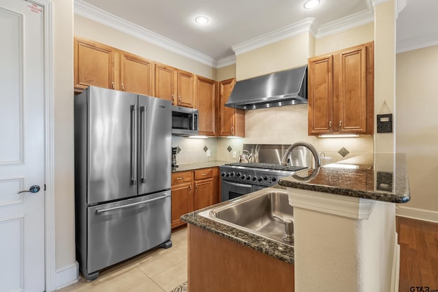 kitchen with stainless steel appliances, dark stone counters, kitchen peninsula, wall chimney exhaust hood, and ornamental molding