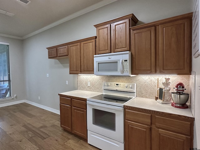 2509 Guinn Farms Rd, Tyler, TX 75707 - kitchen featuring white appliances, wood finished floors, ornamental molding, backsplash, and brown cabinets