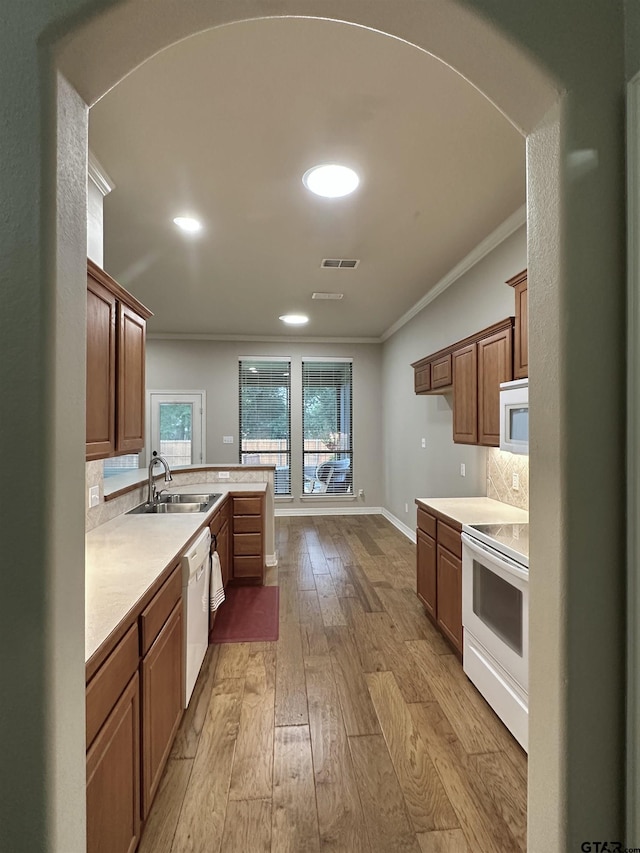 2509 Guinn Farms Rd, Tyler, TX 75707 - kitchen featuring white appliances, ornamental molding, wood-type flooring, light countertops, and a peninsula