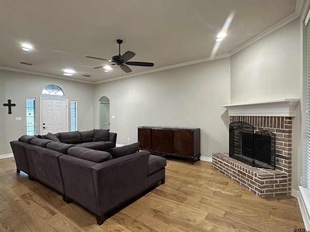 2509 Guinn Farms Rd, Tyler, TX 75707 - living area featuring light wood-style flooring, crown molding, arched walkways, a ceiling fan, and a fireplace
