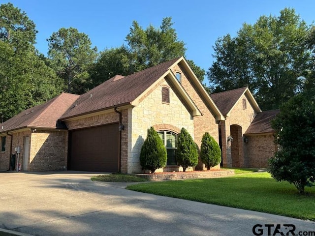 3673 Southwood Dr, Tyler, TX 75707 - view of front of house with a front lawn, stone siding, roof with shingles, an attached garage, and driveway