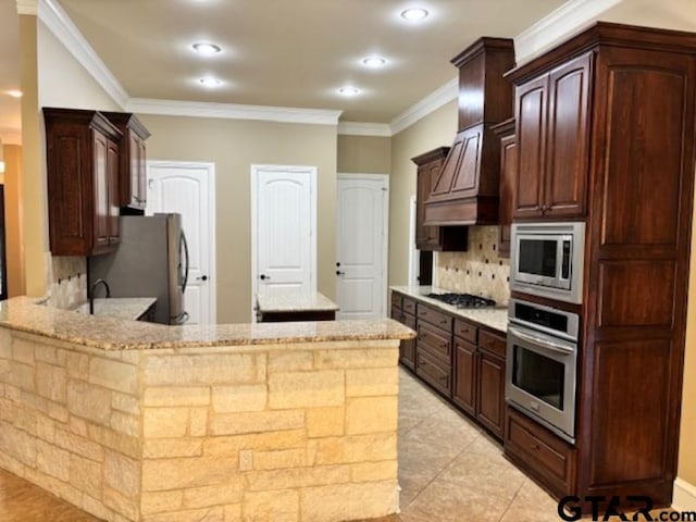 3673 Southwood Dr, Tyler, TX 75707 - kitchen featuring light stone countertops, stainless steel appliances, a peninsula, decorative backsplash, and ornamental molding