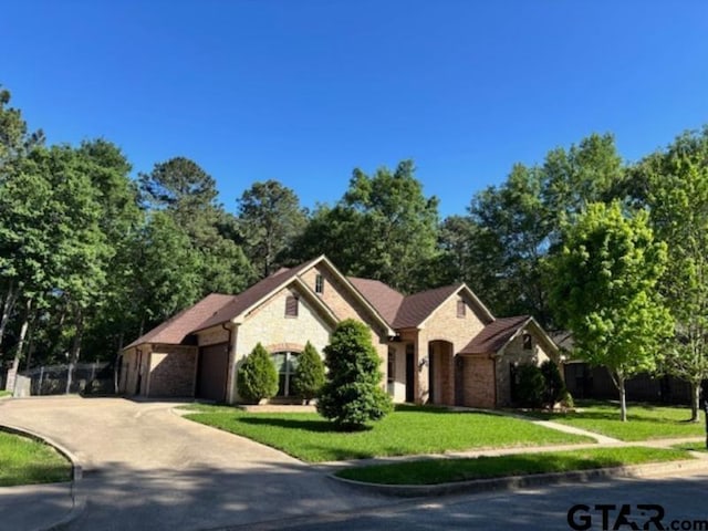 3673 Southwood Dr, Tyler, TX 75707 - ranch-style home featuring a front yard, brick siding, concrete driveway, an attached garage, and stone siding