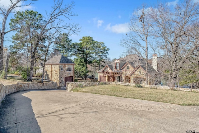 tudor-style house featuring a front lawn and a garage