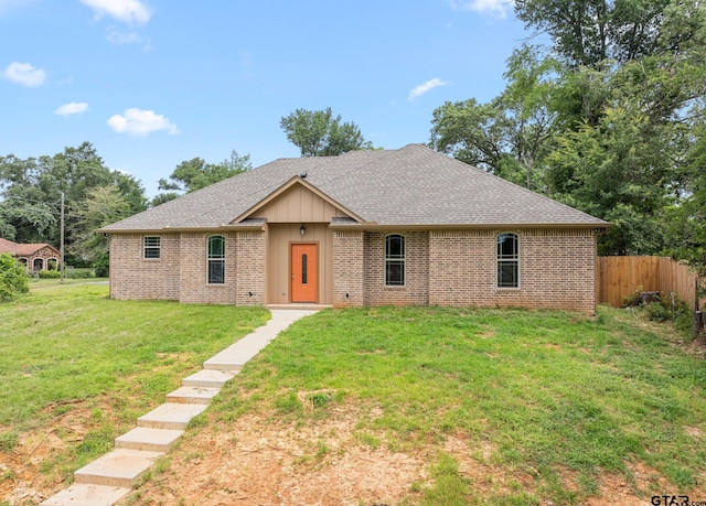 single story home featuring roof with shingles, fence, a front lawn, and brick siding