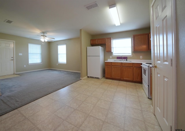 kitchen with white appliances, ceiling fan, a wealth of natural light, and light colored carpet