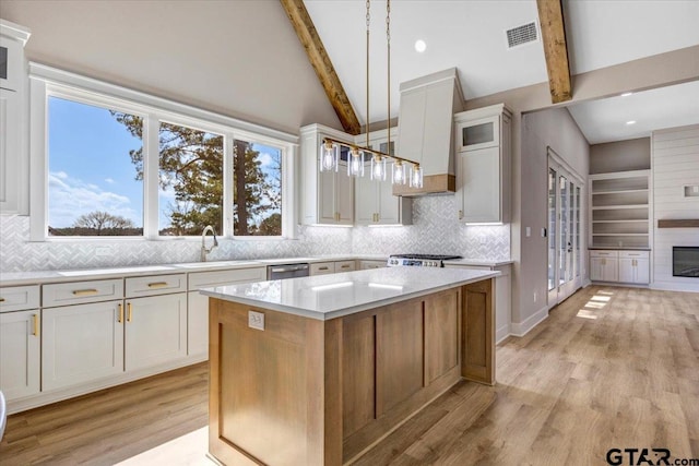 kitchen featuring light hardwood / wood-style flooring, hanging light fixtures, a fireplace, white cabinets, and a kitchen island