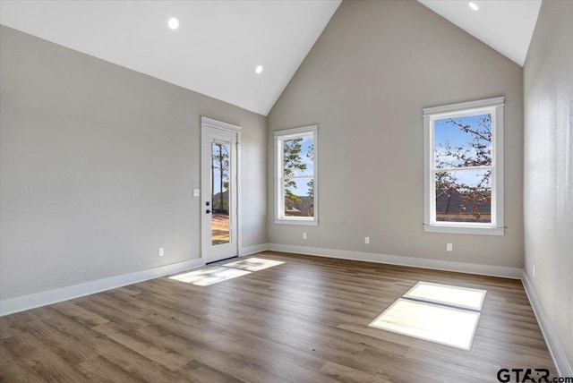 empty room with wood-type flooring and high vaulted ceiling