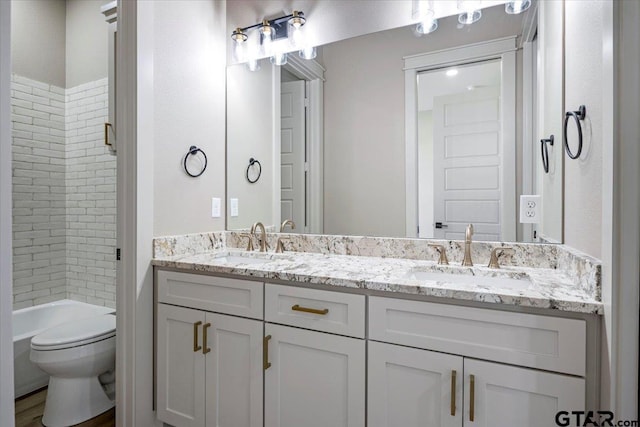 full bathroom featuring vanity, tiled shower / bath combo, and toilet