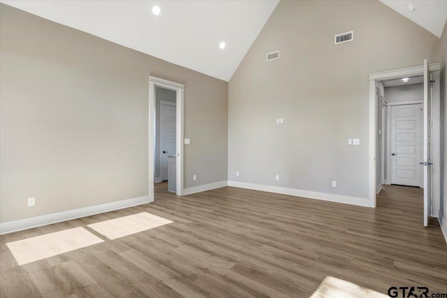 spare room with high vaulted ceiling and light hardwood / wood-style flooring