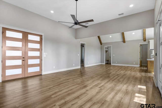 unfurnished living room with lofted ceiling with beams, light hardwood / wood-style flooring, ceiling fan, and french doors