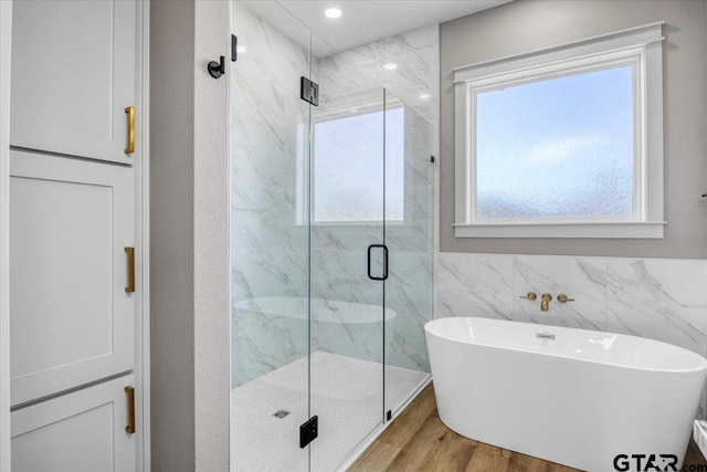 bathroom featuring tile walls, hardwood / wood-style flooring, and shower with separate bathtub