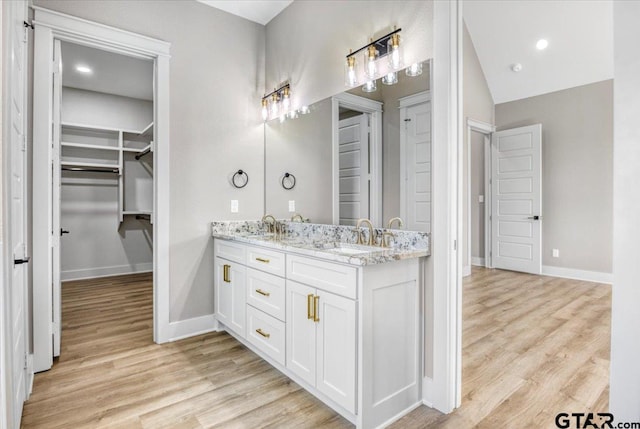 bathroom with vaulted ceiling, vanity, and hardwood / wood-style floors