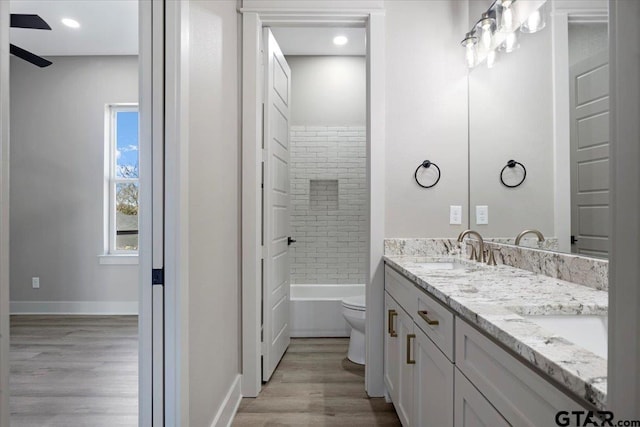 full bathroom featuring vanity, toilet, tiled shower / bath combo, and hardwood / wood-style floors