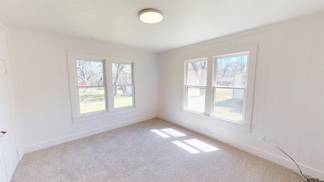 spare room featuring carpet flooring, baseboards, and a healthy amount of sunlight