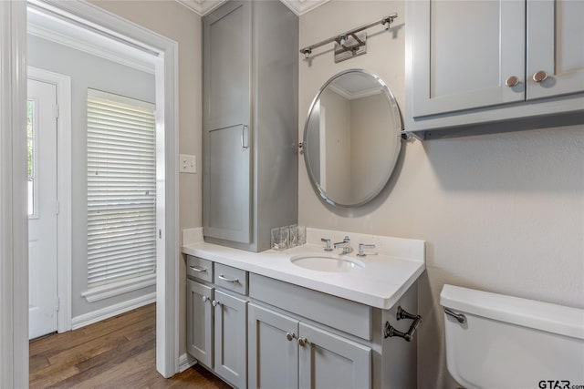 bathroom with hardwood / wood-style floors, vanity, toilet, and crown molding