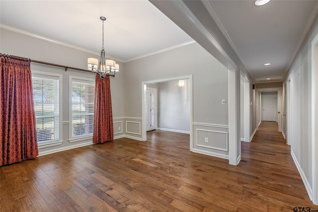 unfurnished dining area with dark hardwood / wood-style flooring, ornamental molding, and an inviting chandelier