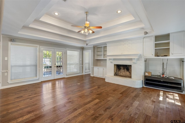 unfurnished living room with a fireplace, french doors, a tray ceiling, and ceiling fan