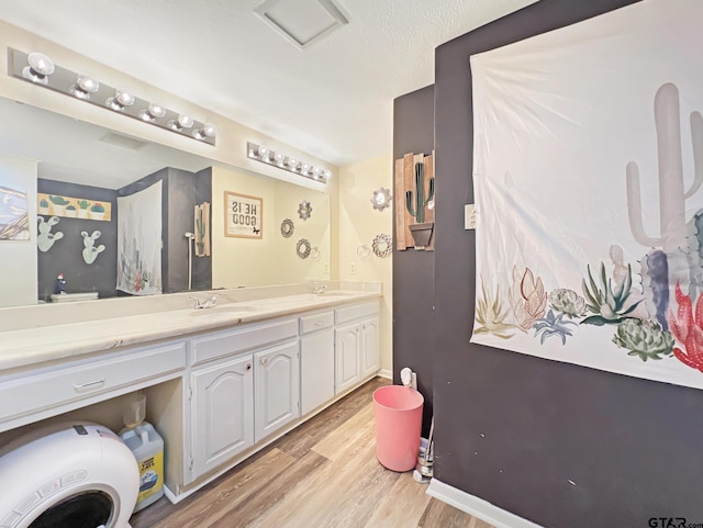 full bath with double vanity, a sink, baseboards, and wood finished floors