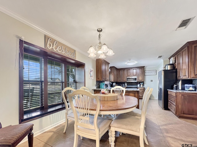 dining space featuring light tile patterned floors, ornamental molding, visible vents, and an inviting chandelier