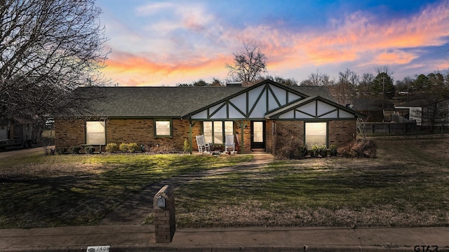 view of front of house featuring brick siding, a yard, a chimney, and roof with shingles