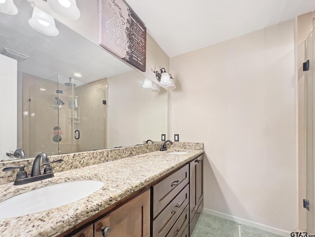 bathroom with baseboards, double vanity, a sink, and a shower stall