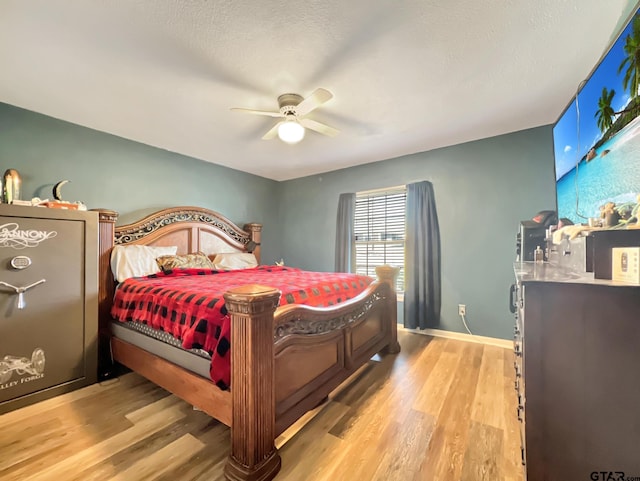 bedroom with light wood-type flooring, ceiling fan, baseboards, and a textured ceiling