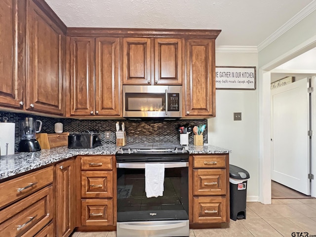 kitchen featuring crown molding, stainless steel appliances, decorative backsplash, light tile patterned flooring, and light stone countertops