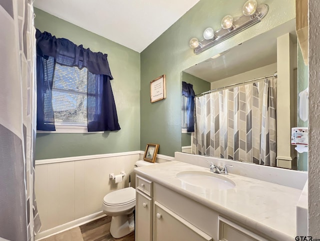 full bath featuring wainscoting, vanity, toilet, and wood finished floors