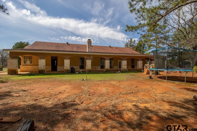 rear view of property with a trampoline