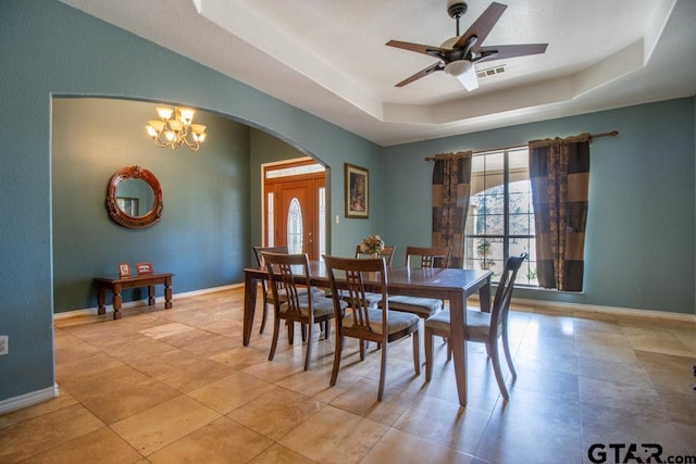 dining space featuring ceiling fan with notable chandelier and a raised ceiling