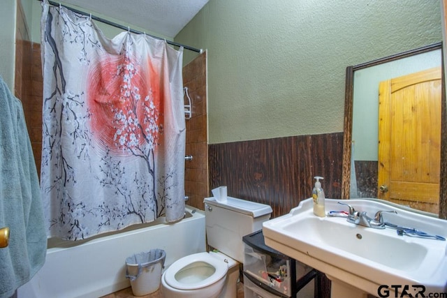 full bathroom featuring a textured ceiling, shower / bathtub combination with curtain, sink, and toilet