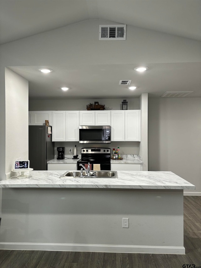 kitchen featuring kitchen peninsula, appliances with stainless steel finishes, dark hardwood / wood-style flooring, white cabinetry, and lofted ceiling