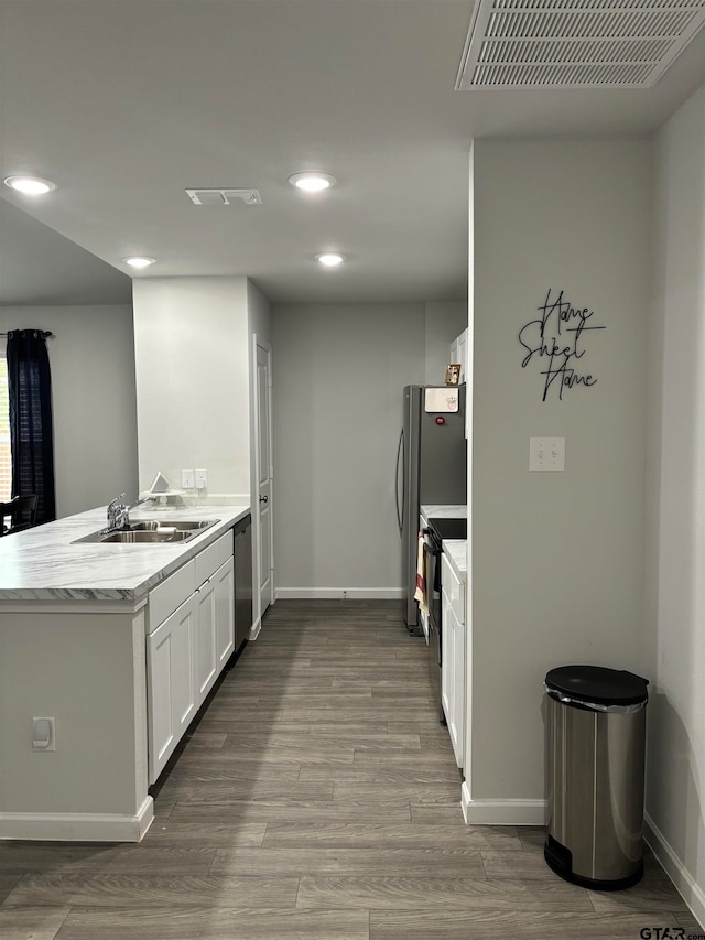 kitchen featuring hardwood / wood-style floors, white cabinets, stainless steel dishwasher, black / electric stove, and kitchen peninsula