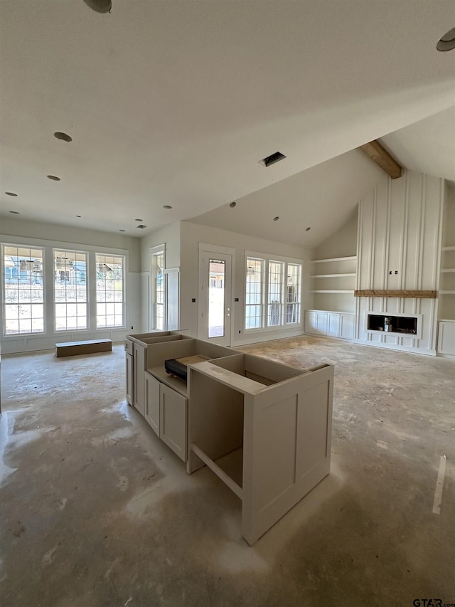 kitchen featuring a kitchen island, vaulted ceiling with beams, white cabinetry, and a healthy amount of sunlight