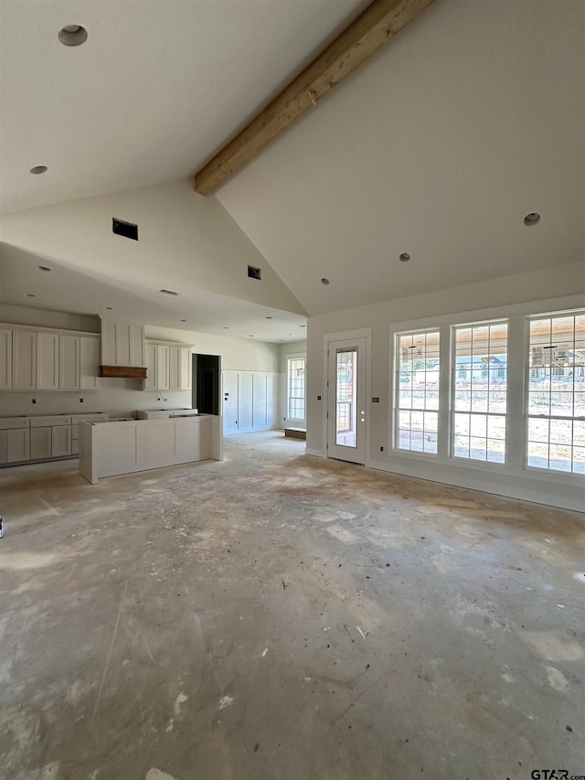 unfurnished living room with beamed ceiling and high vaulted ceiling