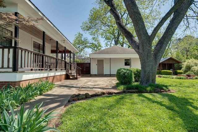 view of yard with covered porch, ceiling fan, and fence