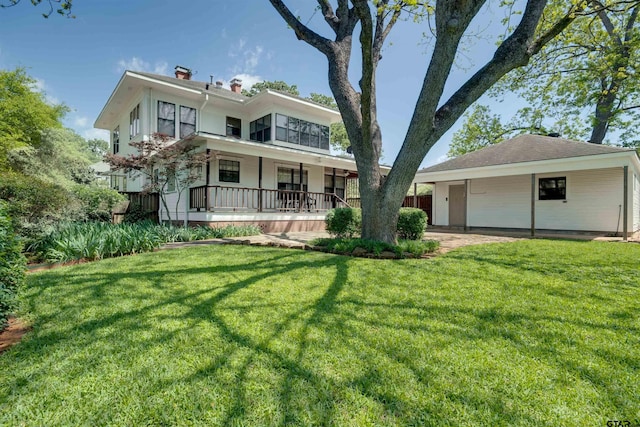 view of front facade featuring a chimney, covered porch, and a front yard