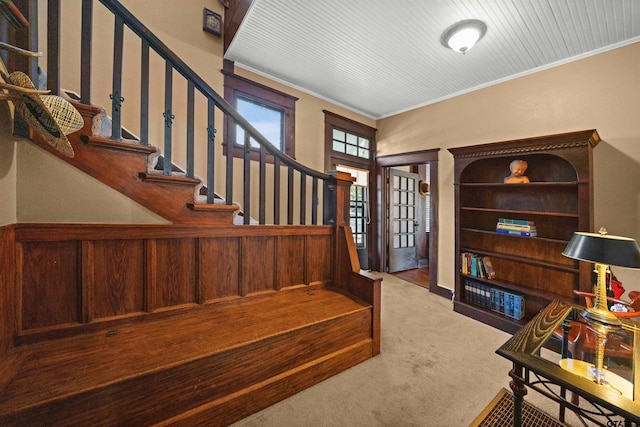staircase with crown molding, carpet floors, and a wainscoted wall