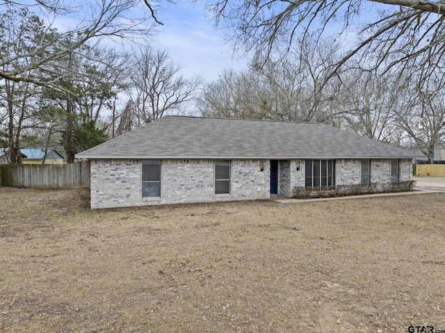 view of front of house featuring brick siding, a shingled roof, and fence